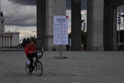 Москва.  Юноша на велосипеде у главного входа  ВДНХ.