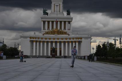 Москва.  Посетители катаются на самокатах на ВДНХ.