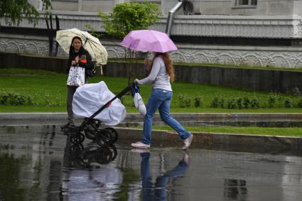 Москва.  Прохожие гуляют у  во время дождя.