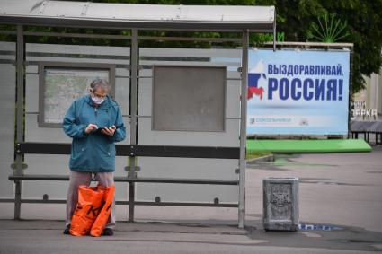 Москва.  Мужчина в медицинской маске на остановке общественного транспорта.