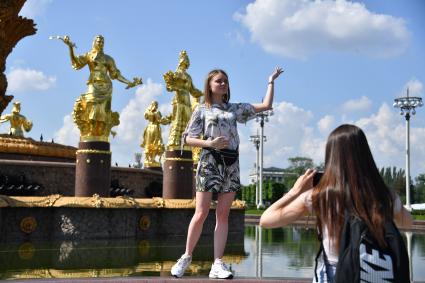 Москва.  Девушка фотографируется у фонтана `Дружба народов` на ВДНХ  после ослабления карантина в условиях эпидемии коронавируса.