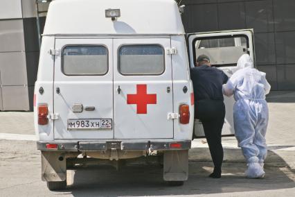 Барнаул. Сотрудник скорой помощи в защитном костюме  сопровождает пациента к автомобилю.
