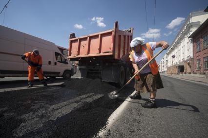 Екатеринбург. Дорожная рабочая-женщина укладывает асфальт на ремонтируемой дороге