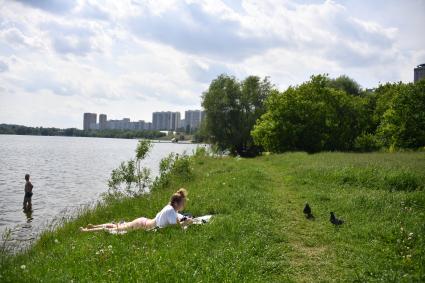 Москва. Девушка загорает на пляже в Строгинской пойме.