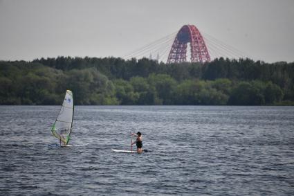 Москва. Молодые люди занимаются SUP-серфингом на пляже в Строгинской пойме.