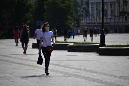 Москва.  Девушка в медицинской маске на улице  после отмены режима самоизоляции, введенного  из-за пандемии коронавируса.