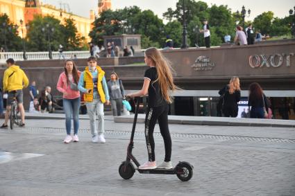 Москва.  Девушка на электросамокате на Манежной площади.