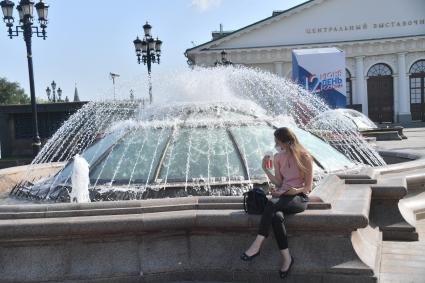 Москва.  Девушка в медицинской маске  у фонтана на Манежной  площади после отмены режима самоизоляции, введенного  из-за пандемии коронавируса.