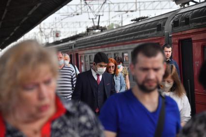 Москва.  Пассажиры пригородных поездов   в медицинских масках на платформе.