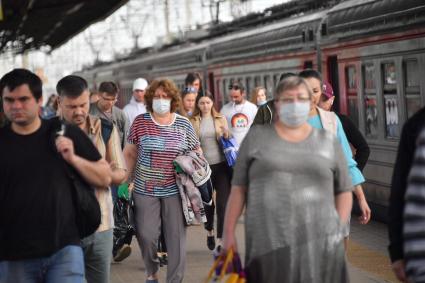 Москва.  Пассажиры пригородных поездов   в медицинских масках на платформе.