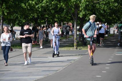 Москва. Молодые люди на самокатах в парке Музеон.