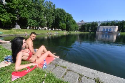 Москва. Девушка с молодым человеком загорают на Патриарших прудах.