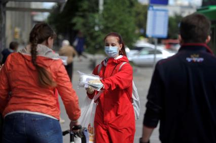 Екатеринбург. Волонтер раздает медицинские маски и буклеты приглашающие участвовать в голосовании по поправкам в Конституцию РФ 1 июля 2020г, во время эпидемии новой коронавирусной инфекции COVID-19