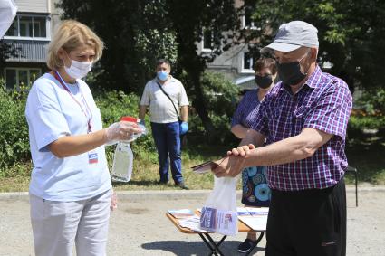 Барнаул. Мужчина дезинфицирует руки перед голосованием по вопросу принятия поправок в Конституцию РФ на мобильном избирательном пункте.