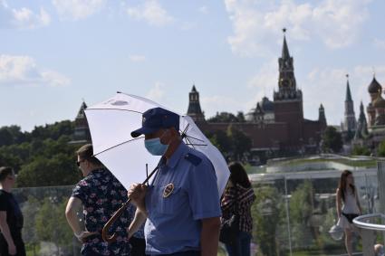 Москва. Мужчина под зонтом в медицинской маске в парке Зарядье.