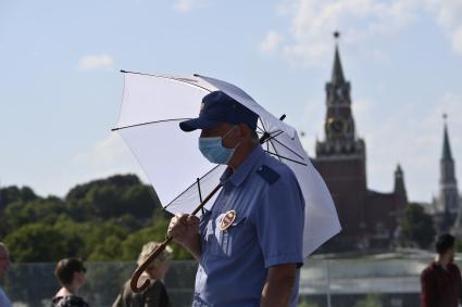 Москва. Мужчина под зонтом в медицинской маске в парке Зарядье.