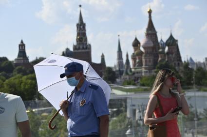 Москва. Мужчина под зонтом в медицинской маске в парке Зарядье.