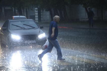 Москва. Мужчина переходит улицу под сильным дождем.