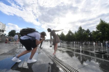 Москва. Молодые люди фотографируются у фонтанов парка Музеон.