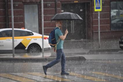 Москва.  Мужчина под зонтом на пешеходном переходе.