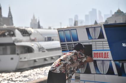 Москва. Мужчина покупает билет на прогулку по Москва-реке.