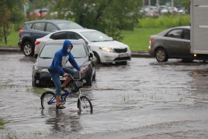 Красноярск. Велосипедист на улице во время дождя.