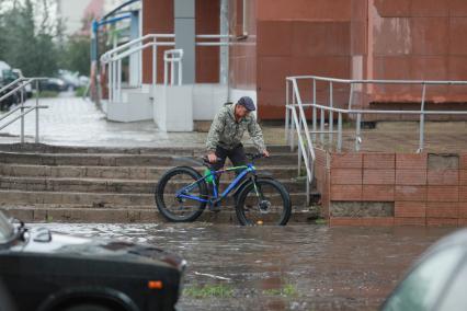 Красноярск. Велосипедист на улице во время дождя.