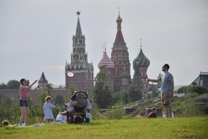 Москва. Женщина с детьми отдыхает на газоне парка Зарядье.