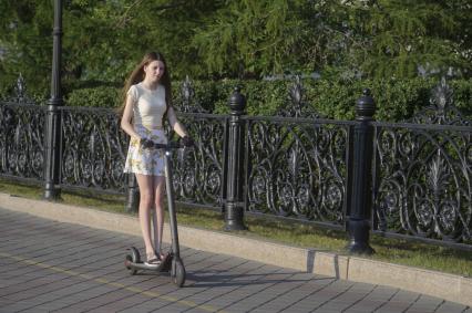 Екатеринбург. Девушка на самокате на набережной реки Исеть во время летней жары
