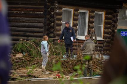 Свердловская область. Нижние Серги. Ликвидация последствий разлива реки Заставка из-за сильного ливня. Река размыла одну из улиц и потоком были смыты несколько домов, гаражей и автомобилей.
Участковый полицейский разговаривает с женщиной живущей в доме в зоне подтопления