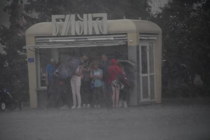 Москва. Прохожие прячутся от дождя под козырьком павильона.
