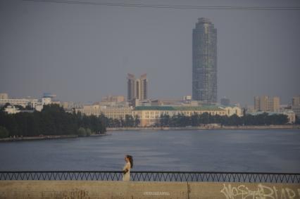 Екатеринбург. Девушка идет по пешеходной части Макаровского моста на фоне городской набережной