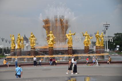 Москва.  Посетители ВДНХ у фонтана `Дружба народов`.