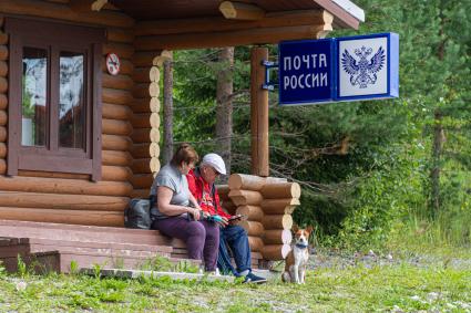 Карелия, Сортавала. Мужчина и женщина у почтового отделения `Почта России ` на территории горного парка `Рускеала`.