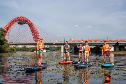 Москва. Молодые люди занимаются SUP-серфингом.