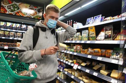 Иркутск.   Молодой человек в медицинской маске в продуктовом магазине.