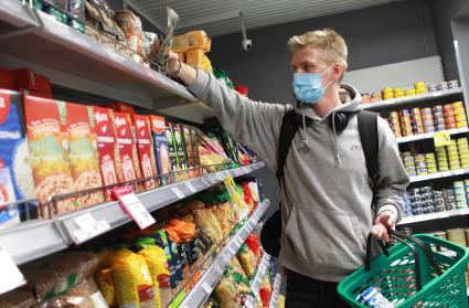 Иркутск.   Молодой человек в медицинской маске в продуктовом магазине.