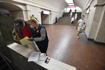 Москва.  Сотрудник метрополитена выписывает штраф пассажиру без медицинской маски.