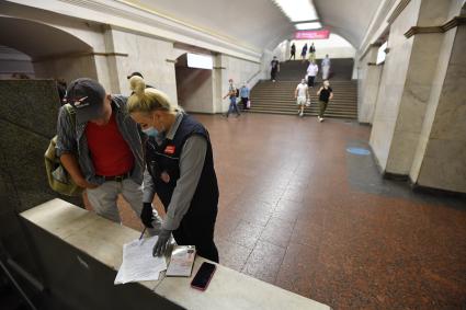 Москва.  Сотрудник метрополитена выписывает штраф пассажиру без медицинской маски.