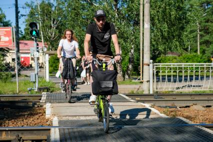 Санкт-Петербург.   Мужчина и женщина на велосипедах переезжают железную дорогу.