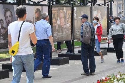 Москва.  Прохожие на открытии фотовыставки, посвященной 85-летию  Олега Табакова на Чистопрудном бульваре.