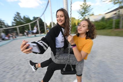 Москва. Девушки фотографируются на качелях.