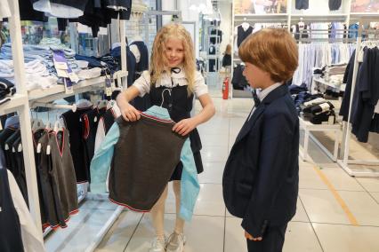 Красноярск. Девочка и мальчик  выбирают  школьную форму в магазине.