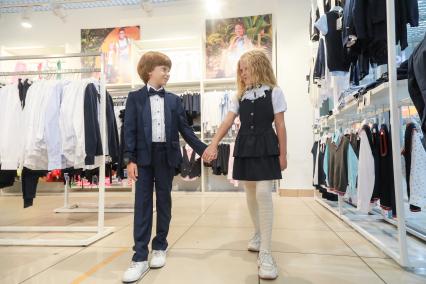 Красноярск. Девочка и мальчик примеряют  школьную форму в магазине.