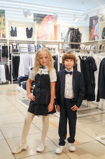 Красноярск. Девочка и мальчик примеряют  школьную форму в магазине.