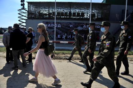 Екатеринбург. Танковый полигон 32-го военного городка. Международный военно-технический форум \'Армия-2020\'. Девушка идет перед военнослужащими