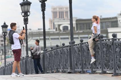 Москва.   Молодые люди фотографируются на Патриаршем мосту.