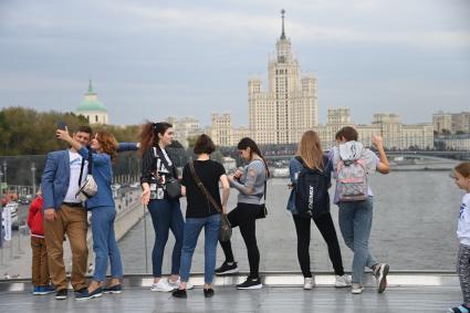 Москва. Молодые люди фотографируются на  Парящем мосту парка Зарядье  во время праздничных гуляний  в День города.