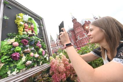 Москва.   Женщина фотографирует  время посещения арт-объекта `Тропа ботанического сада`, расположенного между Манежной площадью и площадью Революции, на праздничных гуляниях в День города.