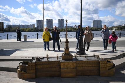Москва. Люди фотографируют макет Северного Речного вокзала, расположенный на набережной.